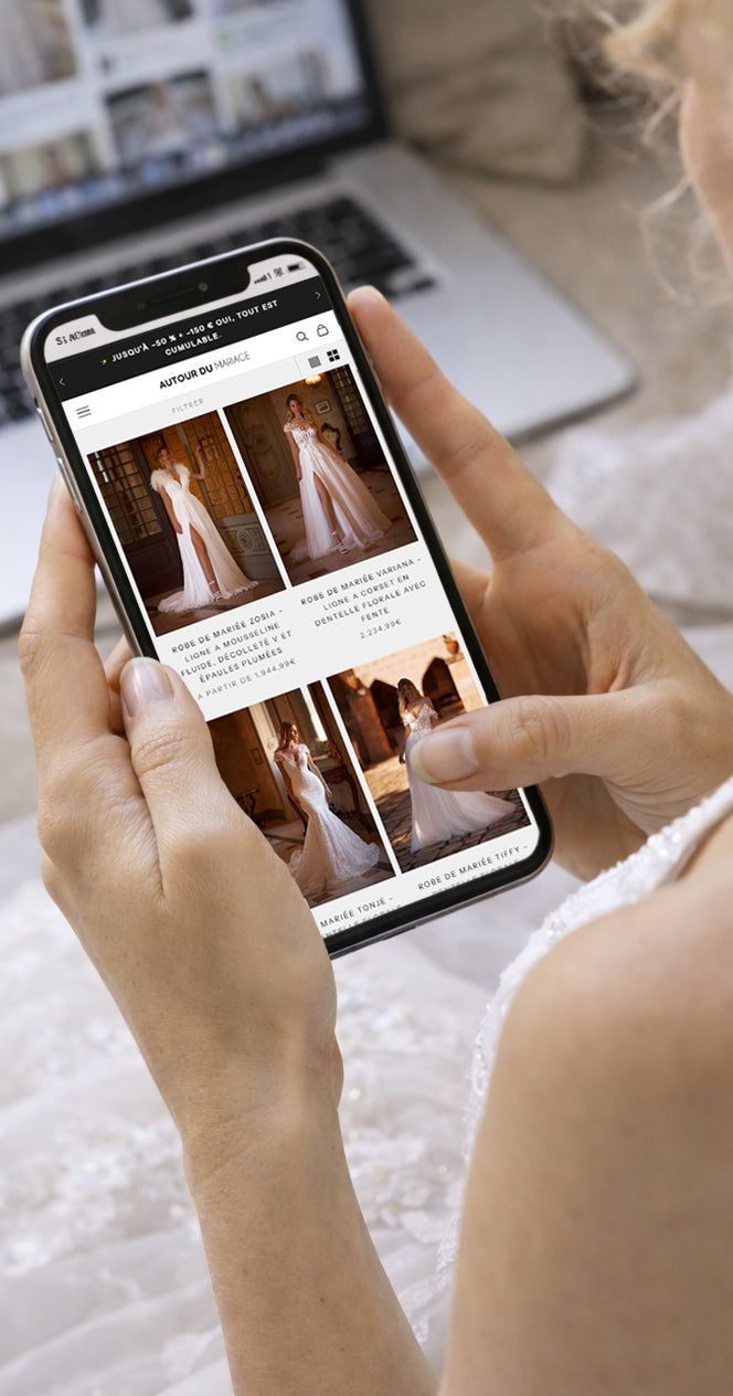 une femme qui choisi sa robe de mariée en ligne sur sont téléphone sur le site internet Autour du mariage