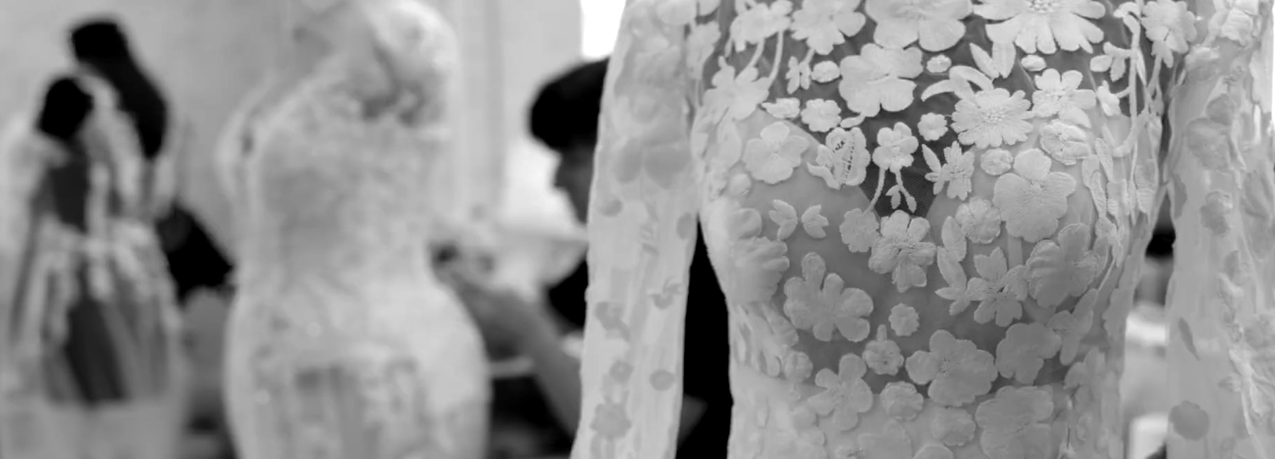 Détail en noir et blanc d’une robe de mariée en dentelle florale lors de sa création dans l’atelier Anna Sposa